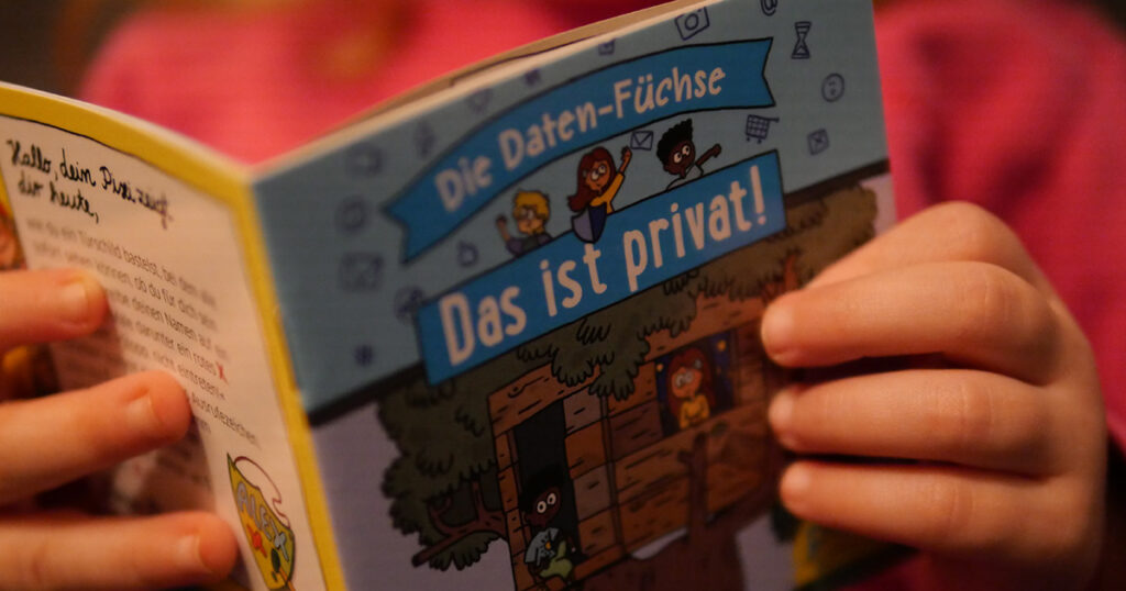 Ein Kind hält das Pixi-Buch »Das ist privat« des BfDI in den Händen