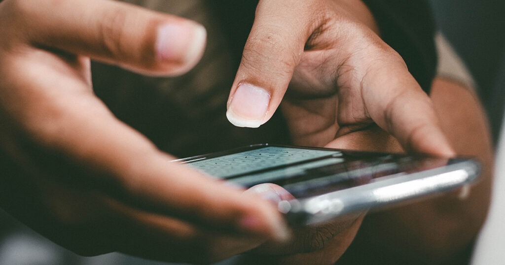 Hände tippen auf einem Smartphone eine Nachricht