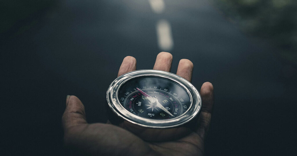 Eine Hand hält einen Kompass auf einer Straße