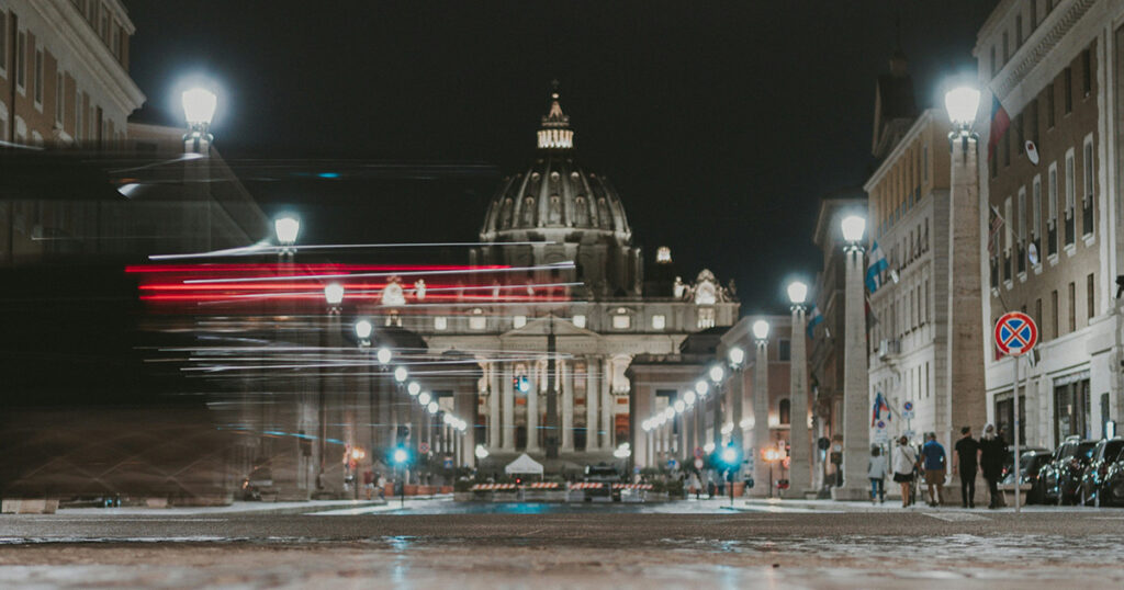 Langzeitbelichtung bei Nacht vor dem Petersdom, im Vordegrund Verkehr