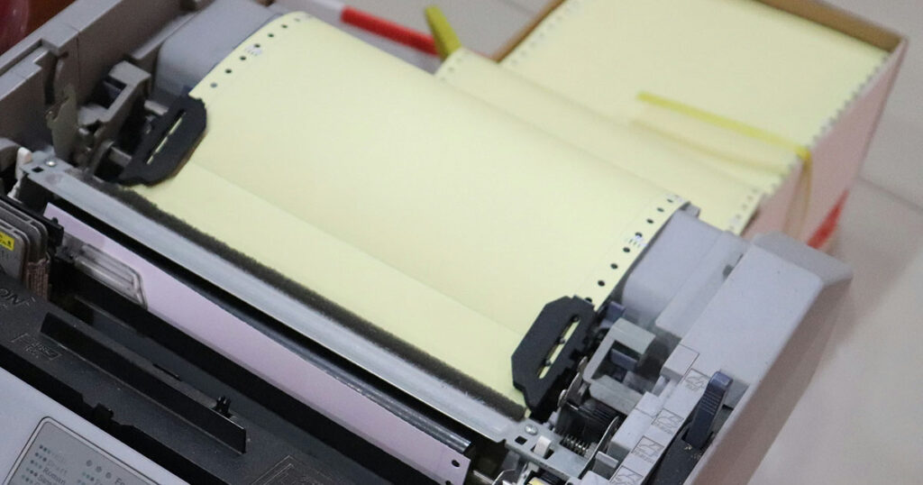 Offener Drucker mit gelbem Endlospapier.