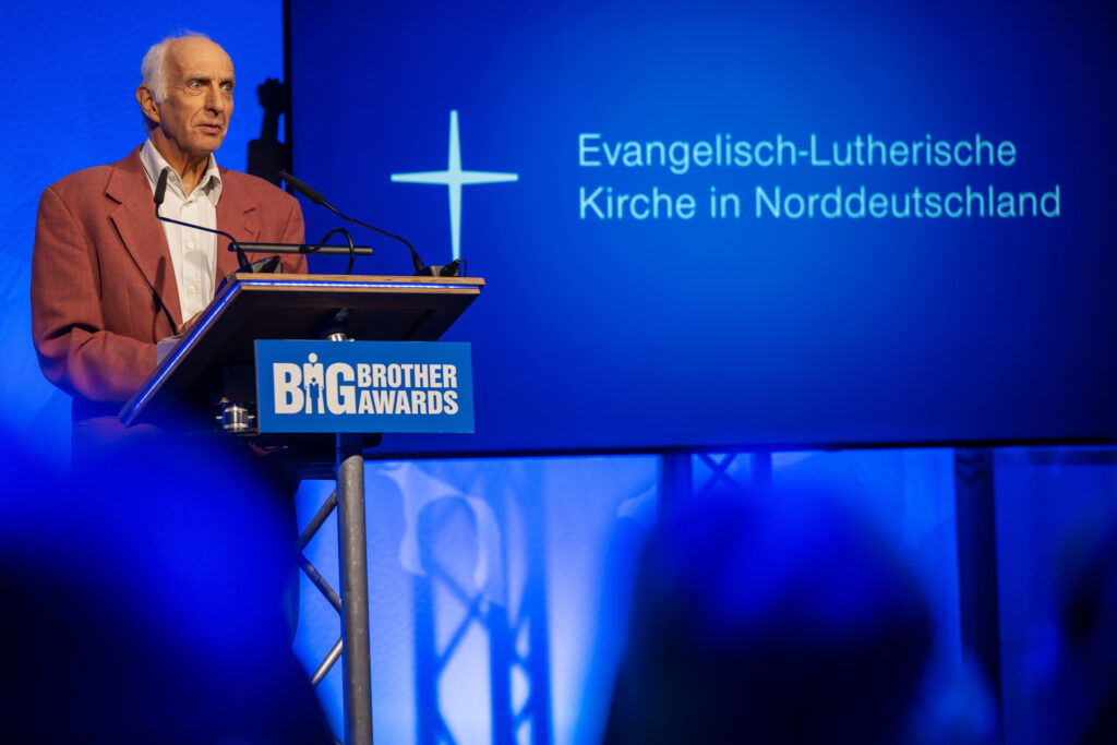 Thilo Weichert hält an einem Rednerpult eine Rede, im Hintergrund das Logo der Nordkirche.